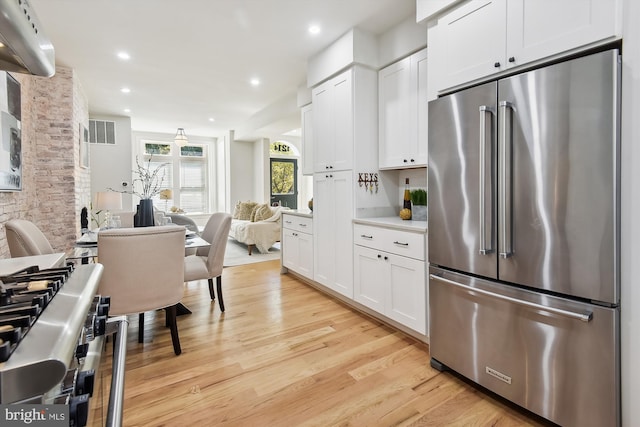 kitchen with light hardwood / wood-style flooring, white cabinets, and stainless steel appliances