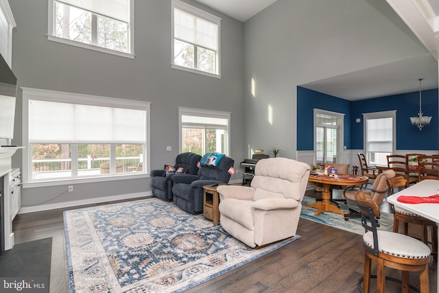 living room featuring dark hardwood / wood-style flooring, a high ceiling, and an inviting chandelier