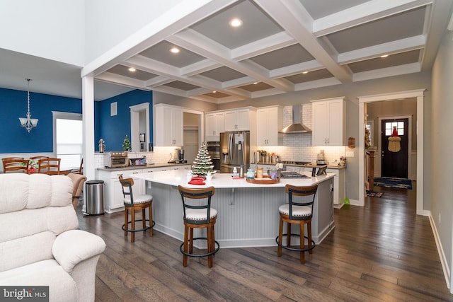 kitchen with appliances with stainless steel finishes, a center island, dark hardwood / wood-style floors, and wall chimney range hood