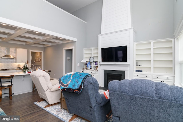 living room featuring beam ceiling, dark hardwood / wood-style flooring, coffered ceiling, and sink