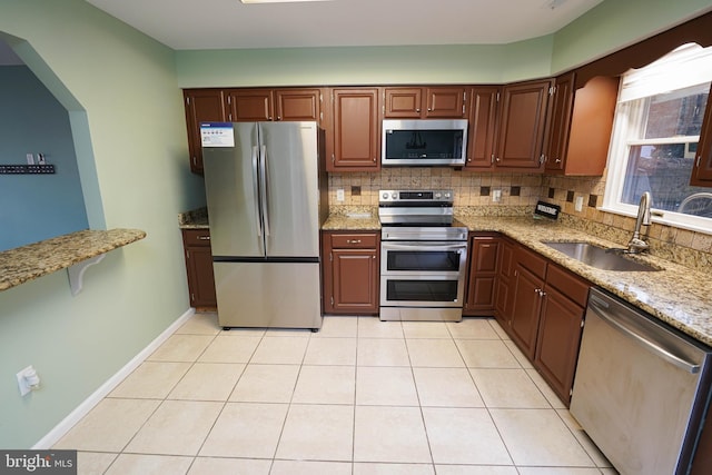 kitchen with light stone countertops, appliances with stainless steel finishes, backsplash, and sink