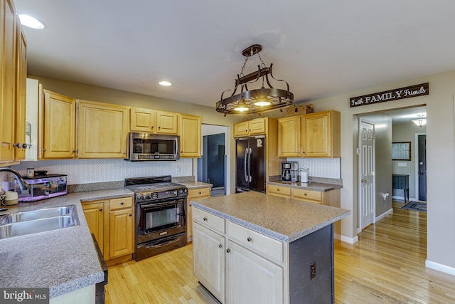 kitchen with sink, a center island, hanging light fixtures, black appliances, and light wood-type flooring