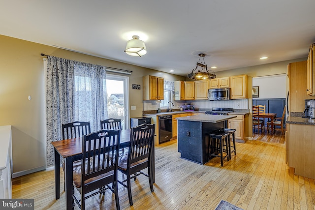 kitchen featuring a center island, backsplash, decorative light fixtures, light hardwood / wood-style floors, and stainless steel appliances