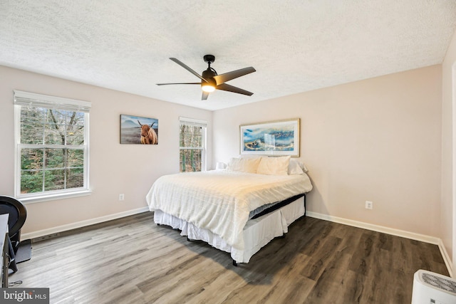 bedroom with dark hardwood / wood-style floors, ceiling fan, and a textured ceiling