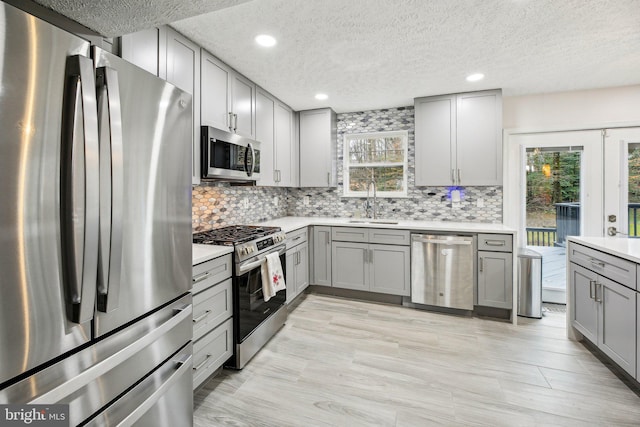 kitchen featuring backsplash, gray cabinets, sink, and appliances with stainless steel finishes