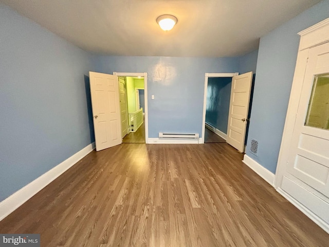 unfurnished bedroom with wood-type flooring and a baseboard heating unit