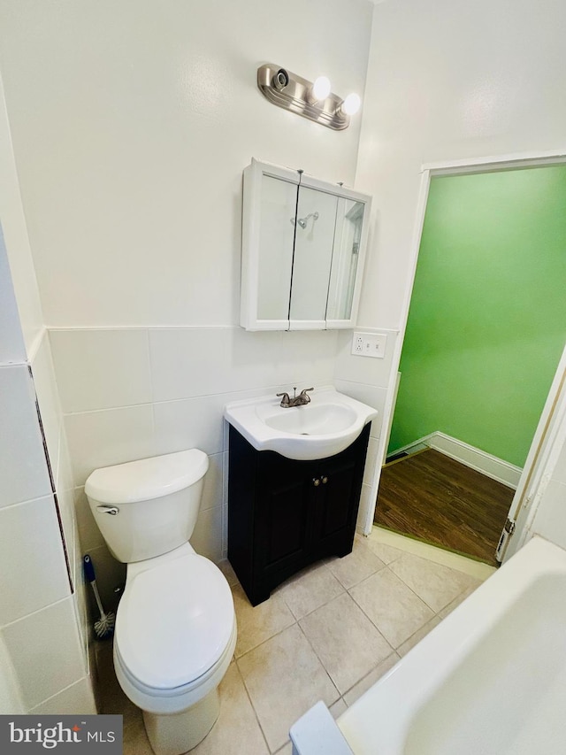 bathroom with tile patterned flooring, vanity, toilet, and tile walls