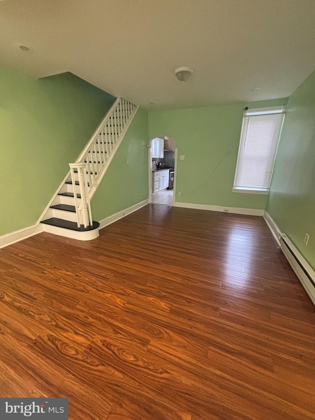 unfurnished living room featuring dark hardwood / wood-style flooring and baseboard heating