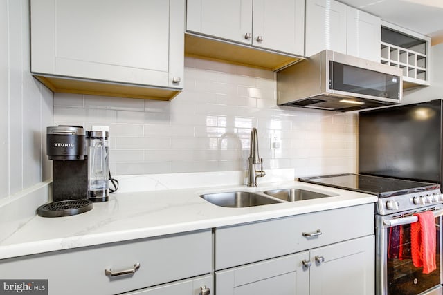 kitchen with tasteful backsplash, light stone counters, stainless steel appliances, sink, and gray cabinets