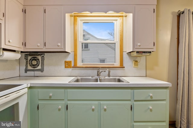 kitchen featuring white cabinets, decorative backsplash, white range, and sink