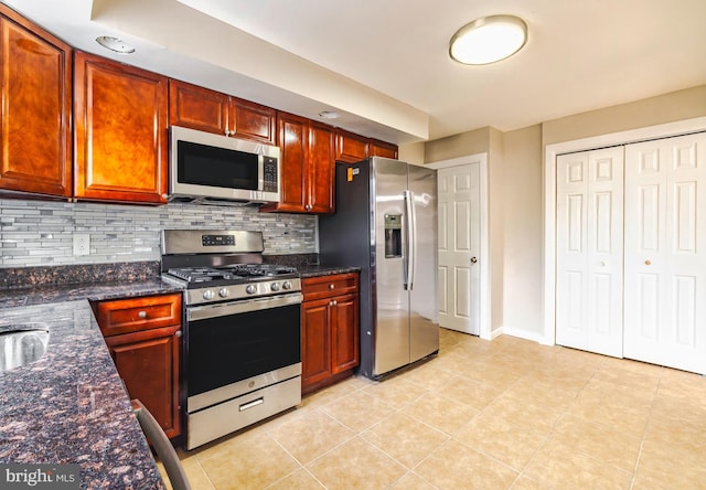 kitchen with decorative backsplash, appliances with stainless steel finishes, dark stone countertops, and light tile patterned flooring