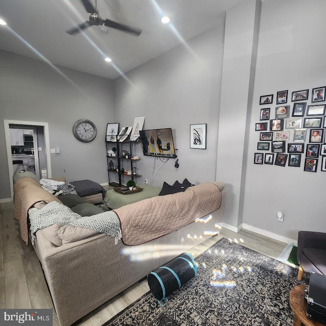 living room with hardwood / wood-style floors, ceiling fan, and a high ceiling