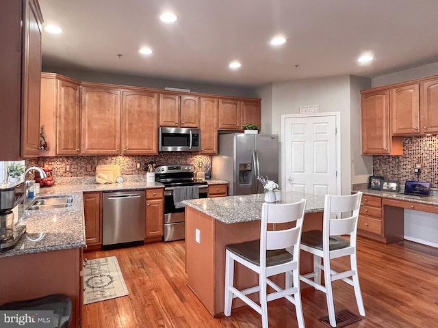 kitchen with sink, stainless steel appliances, a kitchen breakfast bar, light hardwood / wood-style flooring, and a kitchen island