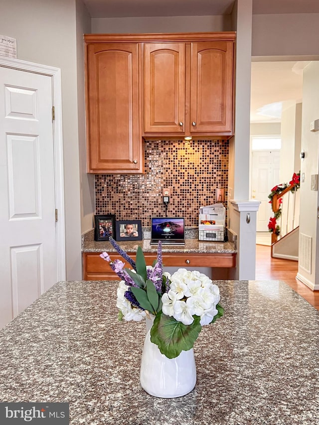 kitchen with dark stone countertops, light wood-type flooring, and backsplash