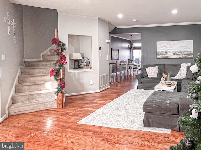 living room with hardwood / wood-style floors, a notable chandelier, and crown molding