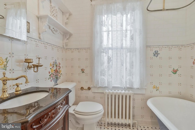 bathroom with radiator, tile walls, vanity, a tub, and toilet