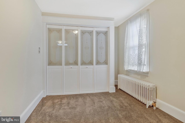 unfurnished bedroom with radiator heating unit, carpet floors, and a closet