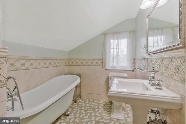 bathroom with tile patterned floors, sink, vaulted ceiling, tile walls, and a tub