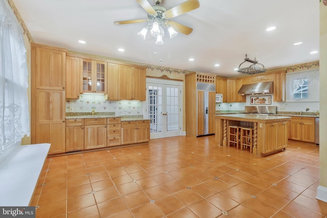 kitchen featuring a kitchen island, ventilation hood, dishwasher, light tile patterned floors, and french doors