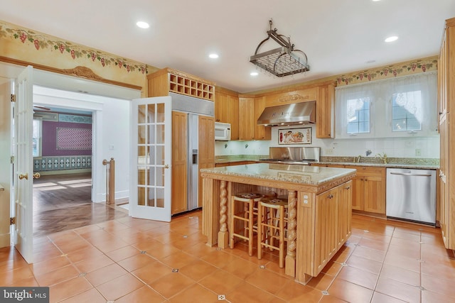 kitchen featuring stainless steel dishwasher, ventilation hood, a center island, and light tile patterned floors