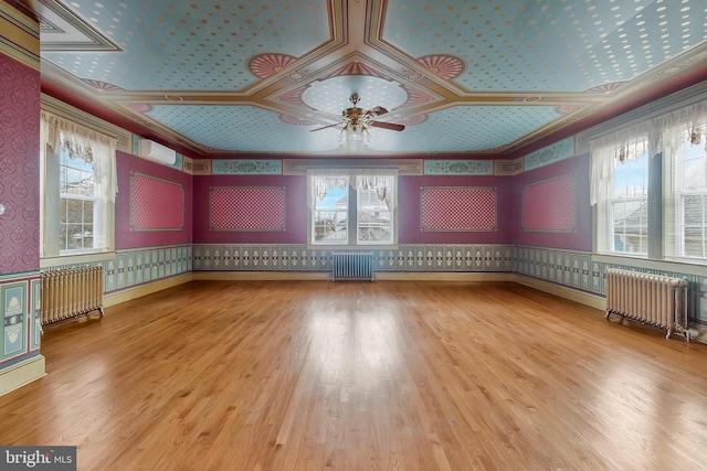 empty room featuring hardwood / wood-style flooring, radiator heating unit, and ceiling fan