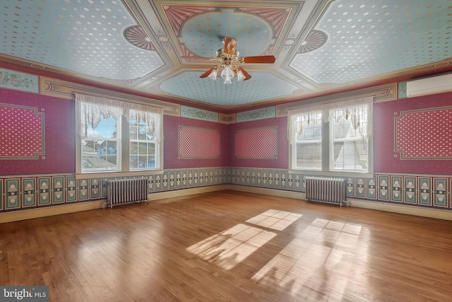 unfurnished room featuring radiator heating unit, wood-type flooring, and plenty of natural light