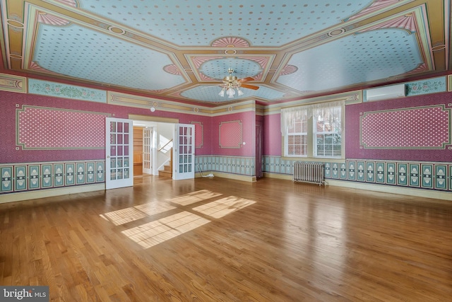 unfurnished living room with french doors, ornamental molding, radiator, ceiling fan, and hardwood / wood-style floors