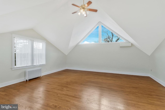 additional living space featuring radiator heating unit, vaulted ceiling, hardwood / wood-style floors, and plenty of natural light