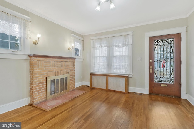 foyer featuring a brick fireplace, crown molding, radiator heating unit, and hardwood / wood-style floors