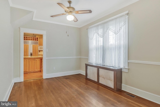 unfurnished room featuring radiator, hardwood / wood-style flooring, ornamental molding, and ceiling fan