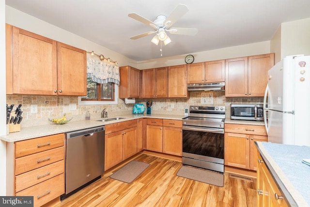 kitchen featuring ceiling fan, sink, light hardwood / wood-style floors, decorative backsplash, and appliances with stainless steel finishes