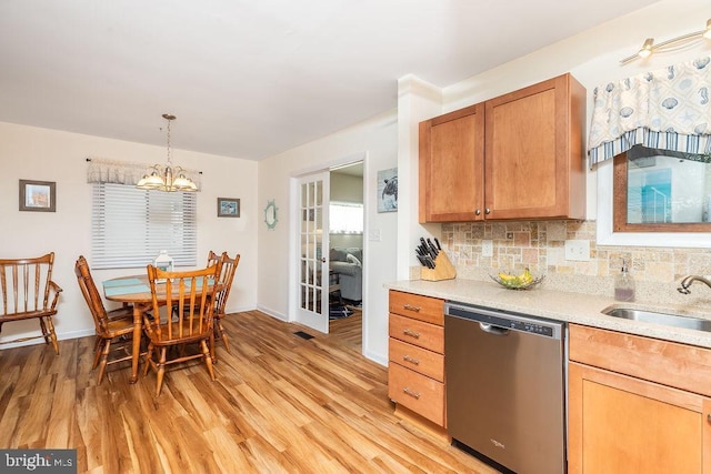 kitchen featuring sink, stainless steel dishwasher, a notable chandelier, light hardwood / wood-style floors, and decorative light fixtures