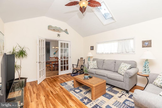 living room featuring french doors, light hardwood / wood-style flooring, ceiling fan, and lofted ceiling with skylight