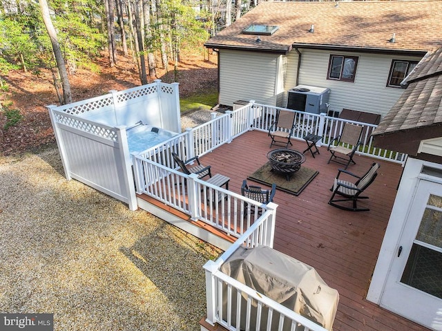 wooden deck with area for grilling, a jacuzzi, and an outdoor fire pit