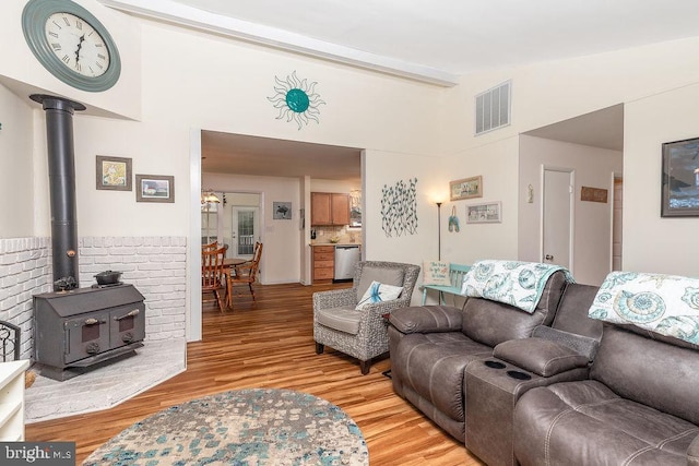 living room with beamed ceiling, light wood-type flooring, and a wood stove