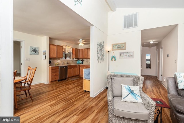 living room featuring beamed ceiling, light hardwood / wood-style flooring, and ceiling fan