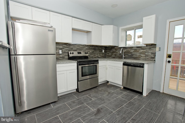 kitchen featuring backsplash, light stone countertops, white cabinets, and stainless steel appliances