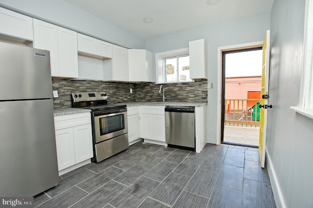 kitchen featuring decorative backsplash, stainless steel appliances, white cabinetry, and light stone countertops