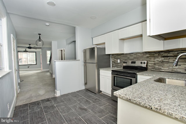 kitchen featuring light stone countertops, appliances with stainless steel finishes, tasteful backsplash, sink, and white cabinetry