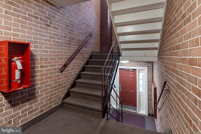 staircase featuring brick wall