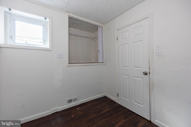 spare room featuring a textured ceiling and dark hardwood / wood-style floors