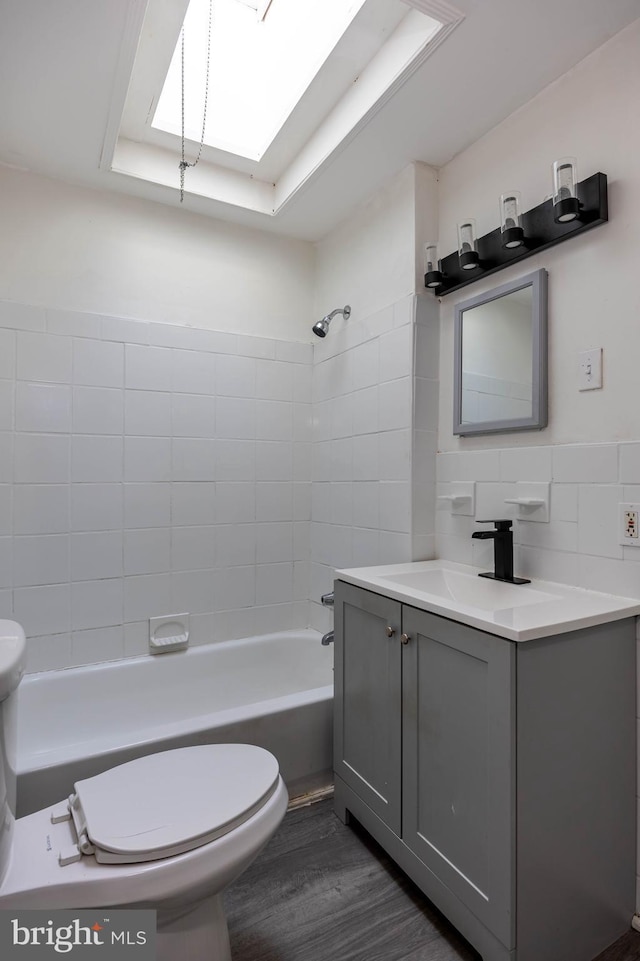 full bathroom with vanity, hardwood / wood-style flooring, toilet, tile walls, and a tray ceiling