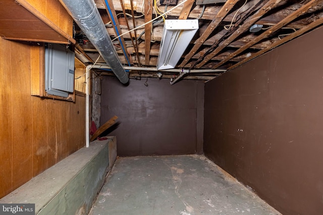 basement with electric panel and wood walls