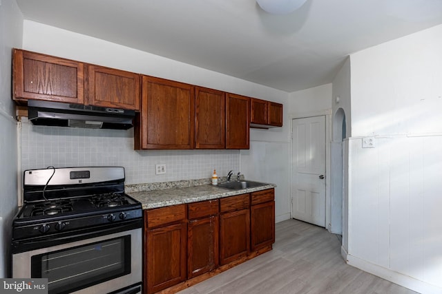 kitchen with gas stove, tasteful backsplash, light hardwood / wood-style flooring, and sink