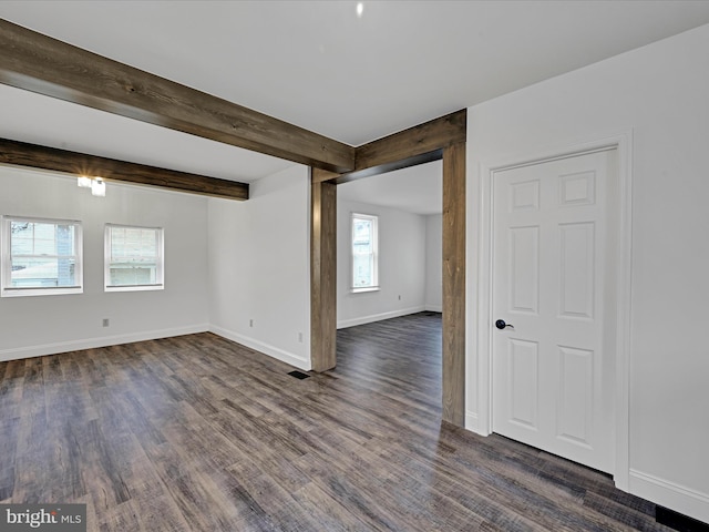 unfurnished room featuring dark hardwood / wood-style flooring and beamed ceiling