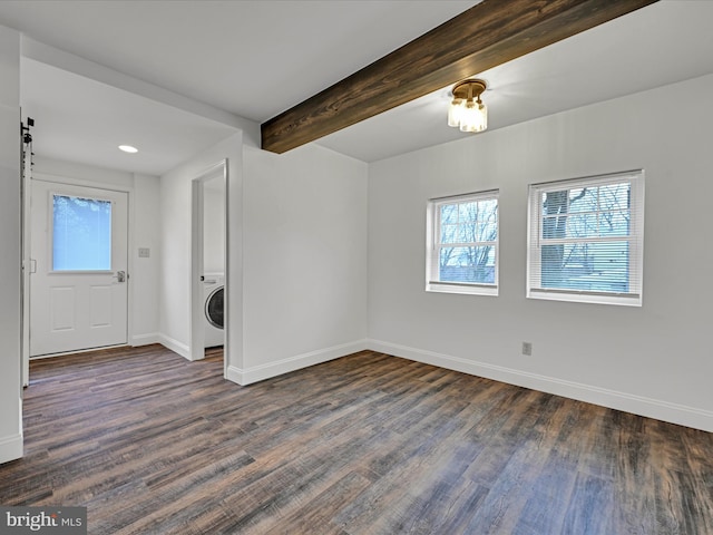 unfurnished room with beam ceiling, washer / clothes dryer, dark wood-type flooring, and a barn door