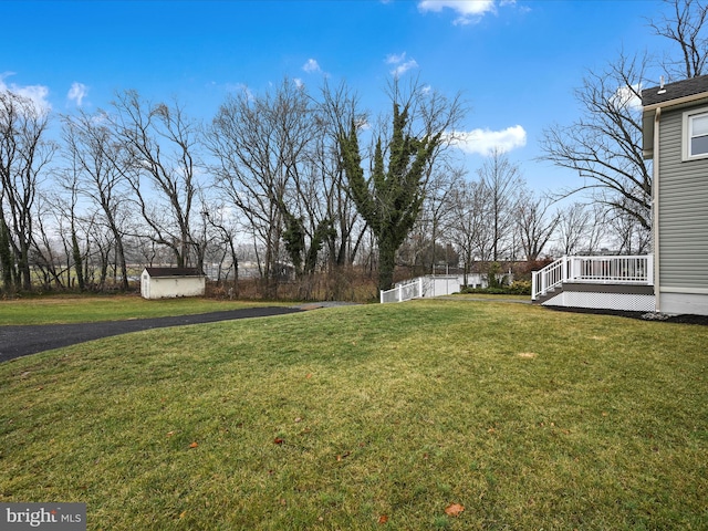 view of yard featuring a storage unit and a wooden deck