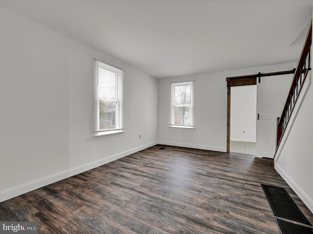 unfurnished room featuring dark hardwood / wood-style flooring and a barn door