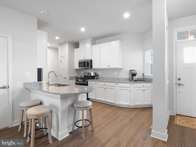373 Guglielma Springett Dr, West Grove, PA 19390 - kitchen with stainless steel appliances, a breakfast bar, light wood-style flooring, white cabinetry, and recessed lighting
