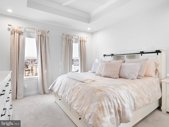 carpeted bedroom featuring a raised ceiling and multiple windows